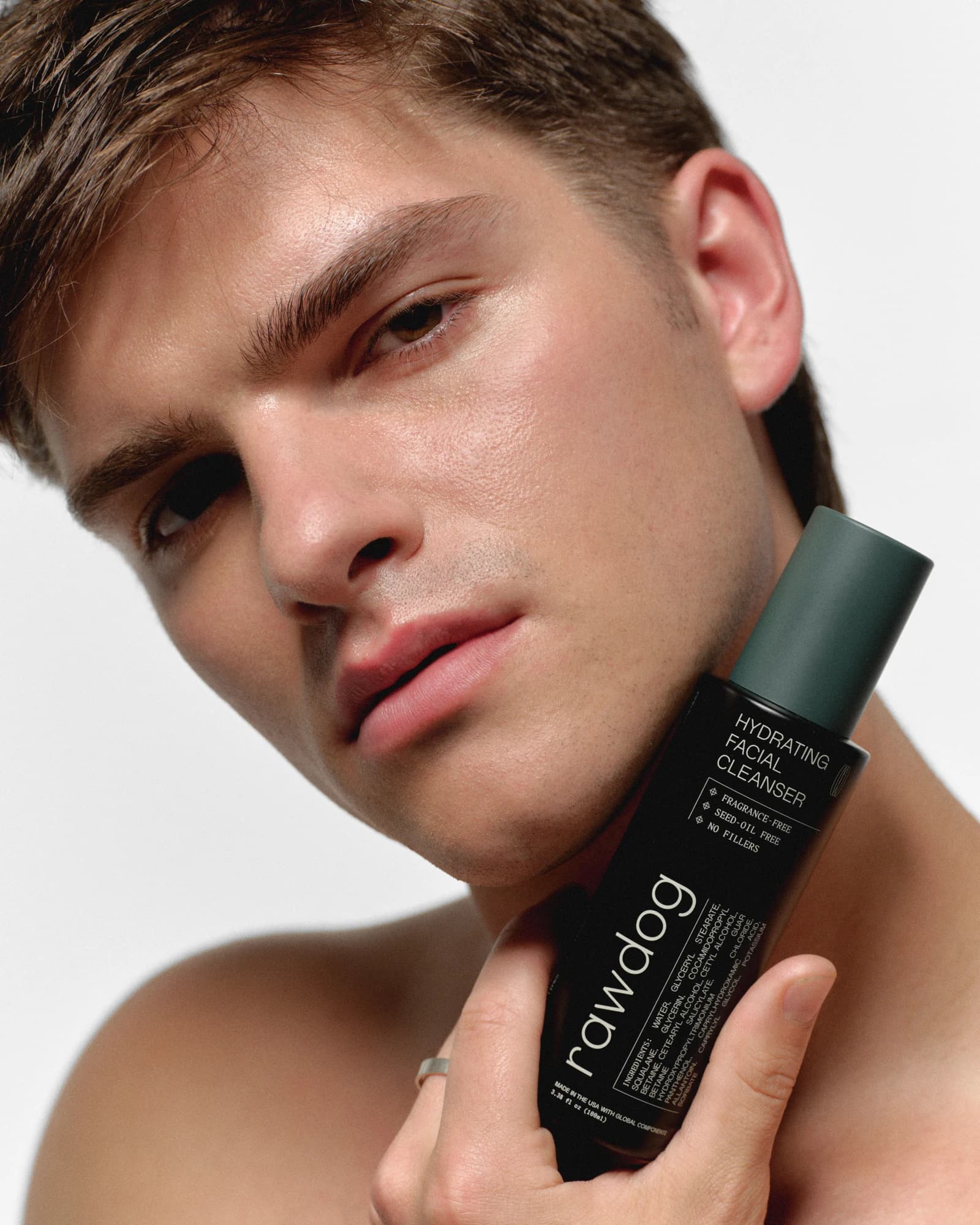 Man holding RAWDOG Hydrating Facial Cleanser beside his face