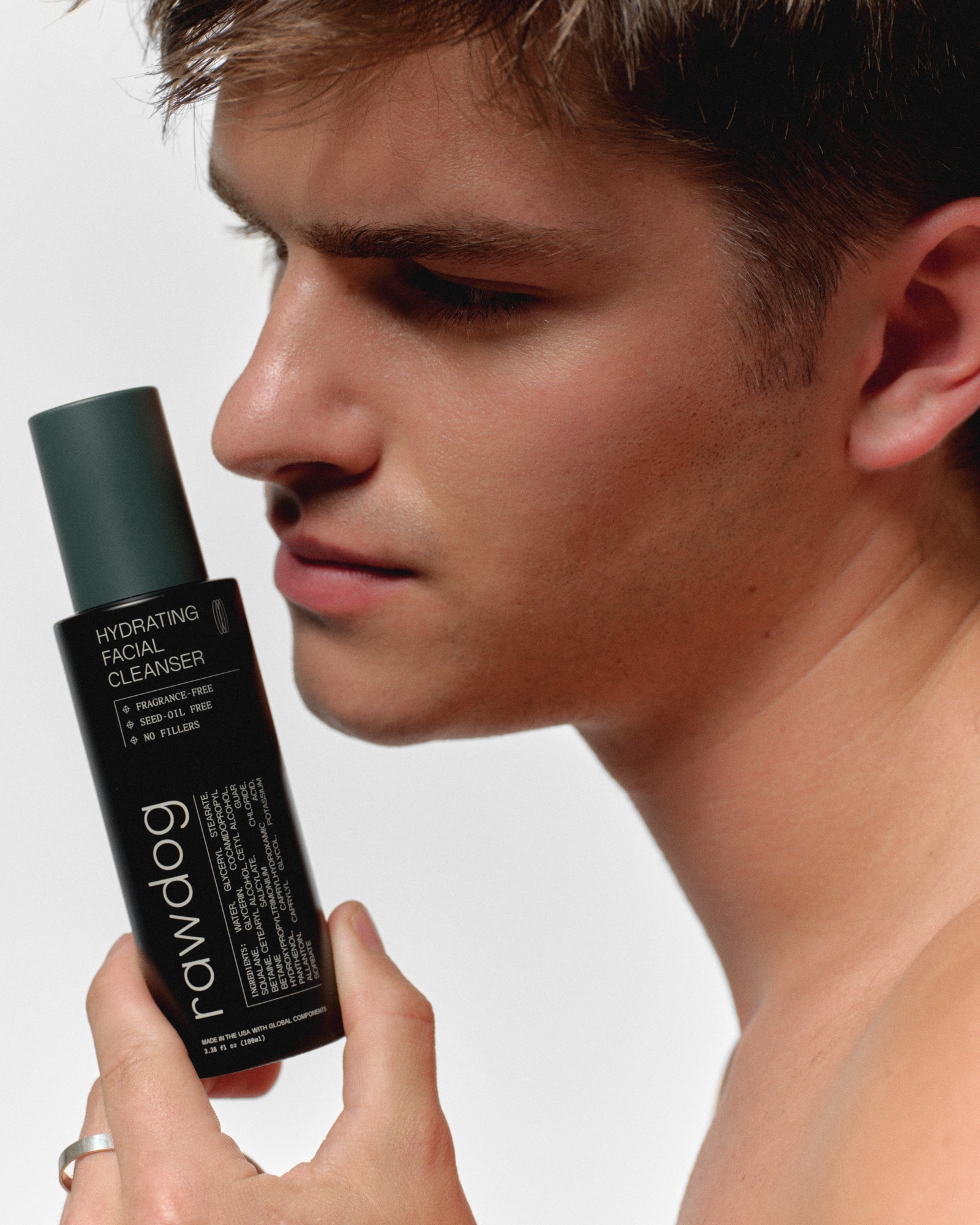 RAWDOG Hydrating Facial Cleanser held beside a man's face