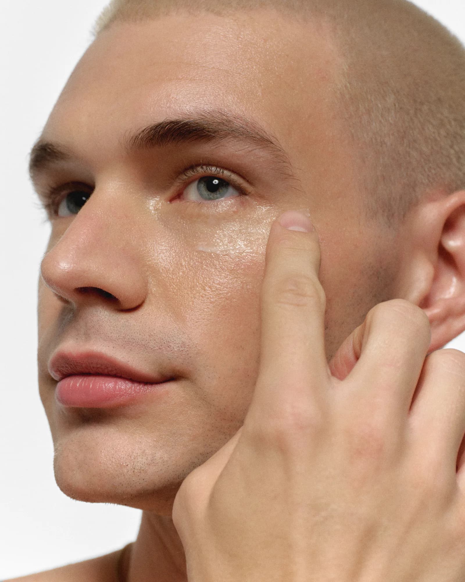 Man applying RAWDOG eye cream beneath his eye